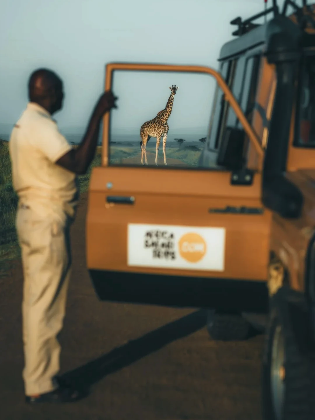 Imagen de un conductor de coche de safari en áfrica de pie observando una girafa